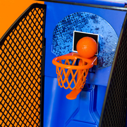 Close-up on the blue, speckled backboard and orange hoop of the arcade basketball game, with a ball balanced on the rim.