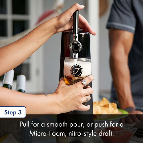 A person uses a black countertop draft beer dispenser to pour a glass of beer at a table set with snacks, including chips and salsa, while another person stands nearby. The text below details step three to pull for a pour or push for foam.