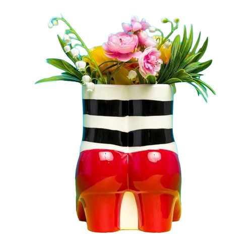 The Wizard of Oz Red Slippers vase seen from behind, with black-and-white striped stockings and a colourful bouquet.