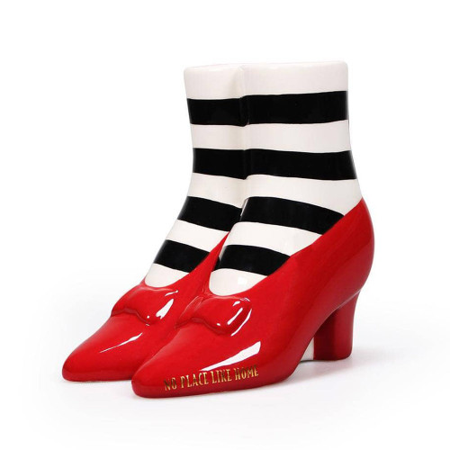 A Wizard of Oz tabletop vase of legs in striped socks and glossy red slippers. The toe reads "No Place Like Home" in gold.