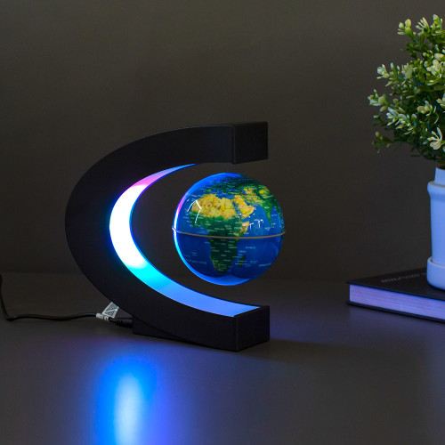 A floating globe levitates inside its C-shaped, multicolour LED-lit stand on a dark desk beside a small potted plant.