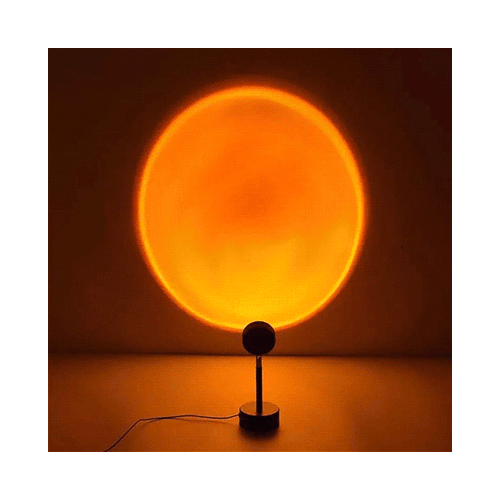 The black Sundown Mood Lamp projects a large, circular warm orange and yellow light onto a wall, mimicking a sunset.