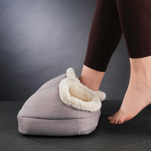Someone slides their bare foot into the grey Vibrating Foot Massager. It has a soft, fluffy, cream-coloured lining.