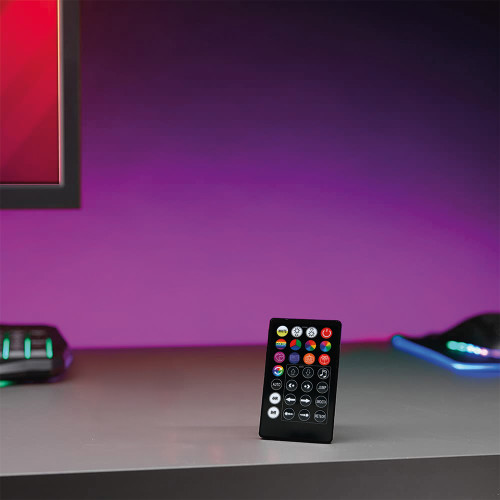 The LED Strip Light remote stands on a desk in a gaming setup, bathing the wall behind in a purple and magenta glow.