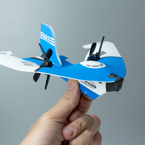 A hand holds a small blue and white remote control stunt plane, showing its twin propellers against a grey background.