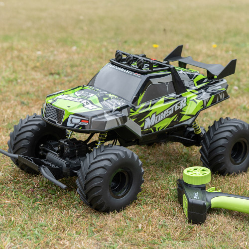 A lime green and black Rock Monster RC truck with large tyres sits on a grassy lawn next to its matching remote controller.