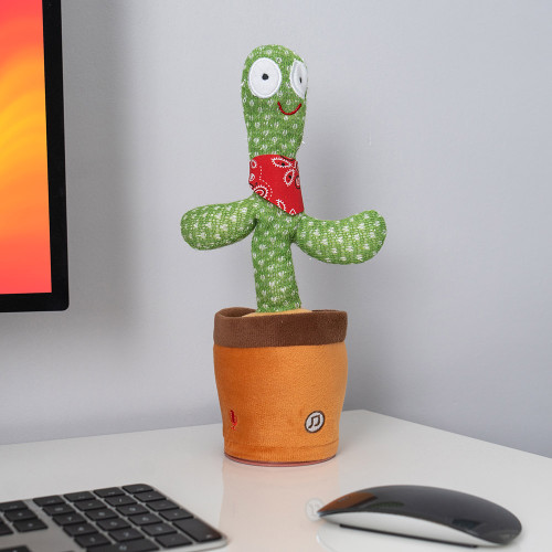 A plush toy cactus with a red bandana sits in a brown pot on a white desk near a computer monitor, keyboard, and mouse.