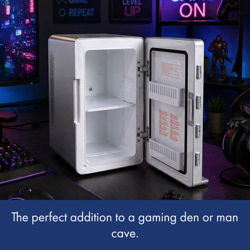 A silver mini-fridge sits open on a desk in a gaming den, its empty interior lit by a nearby monitor and neon signs.