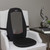 A black Shiatsu Massage Cushion with a grey mesh back panel, strapped onto a white armchair in a modern living room setting.