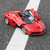A red La Ferrari remote control car sits on a tarmac road, straddling a white line, with its doors and boot open.