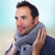 A man wears the soft grey Vibrohug vibrating neck massager, holding it around his neck with a relaxed, contented expression.