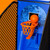 Close-up on the blue, speckled backboard and orange hoop of the arcade basketball game, with a ball balanced on the rim.