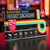 The Electronic Games Advent Calendar, in its retro-styled box, sits on a table in front of a colourful, blurry arcade.
