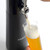 A person pours a golden beer with a thick, foamy head from the black Fizzics DraftPour tap into a tall glass.