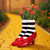 A Wizard of Oz vase shaped like red slippers and striped stockings, filled with red tulips. It is on a yellow brick road.