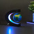 A floating globe levitates inside its C-shaped, multicolour LED-lit stand on a dark desk beside a small potted plant.