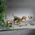 A remote controlled dinosaur toy with glowing red eyes in a running pose on a grey desk, next to its fossil-shaped remote.