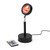 A black Sundown Mood Lamp glowing with a warm red and orange sunset light. The remote control lies nearby.