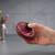 A hand holds the spinning red LED Vortex Spinner, its colourful lights spin quickly. There is a pencil case in the back.