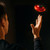 In a dark room, a man watches a red LED Vortex Spinner float and spin above his outstretched hand.