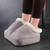 A person wearing the grey fabric Wellbeing foot massager, showing its cosy white fleece-lined interior.
