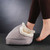 Someone slides their bare foot into the grey Vibrating Foot Massager. It has a soft, fluffy, cream-coloured lining.