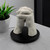 A finished white hand moulding of two clasped hands, displayed on a black circular base.
