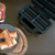 The open Sausage Roll Maker on a kitchen worktop next to a plate of freshly cooked golden-brown sausage rolls with ketchup.