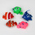 Five colourful toy bubble fish, including an orange clownfish, arranged in a circle against a plain white background.