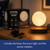 The illuminated Rotating Floating Moon levitates over its wooden base, displayed on a table with its box and power adaptor.