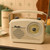 A cream-coloured Retro Radio with a classic circular dial, resting on a kitchen worktop next to a coffee jar.