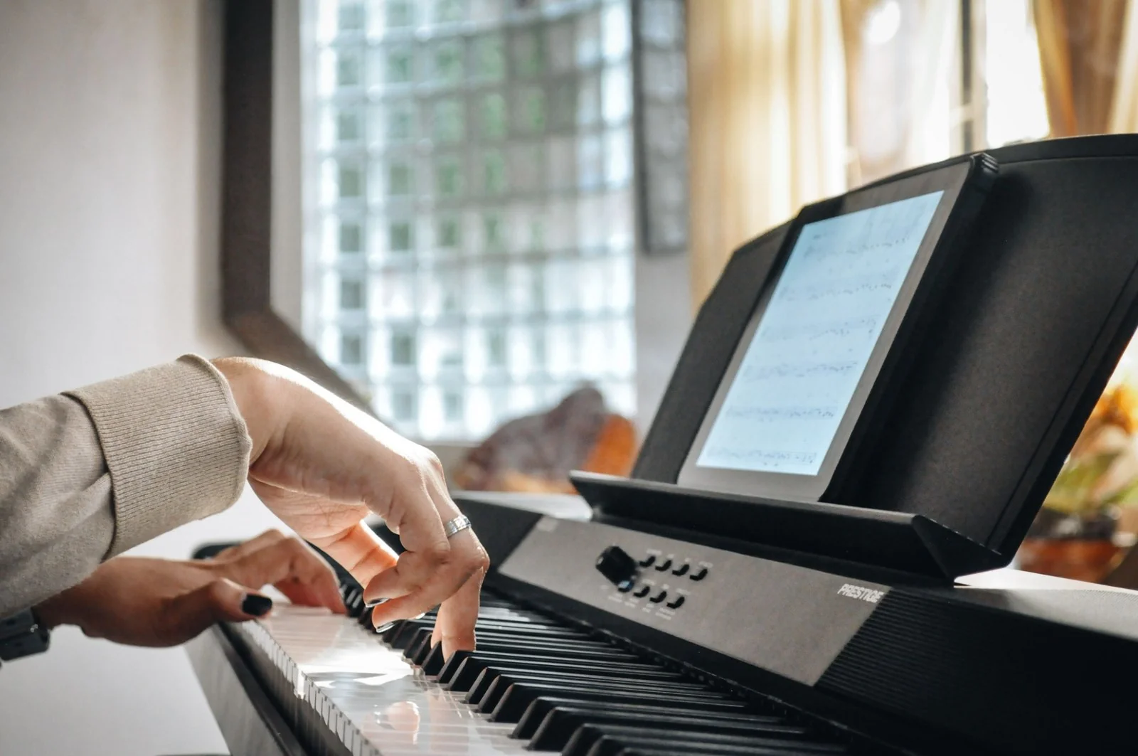 Hands playing a digital piano at home