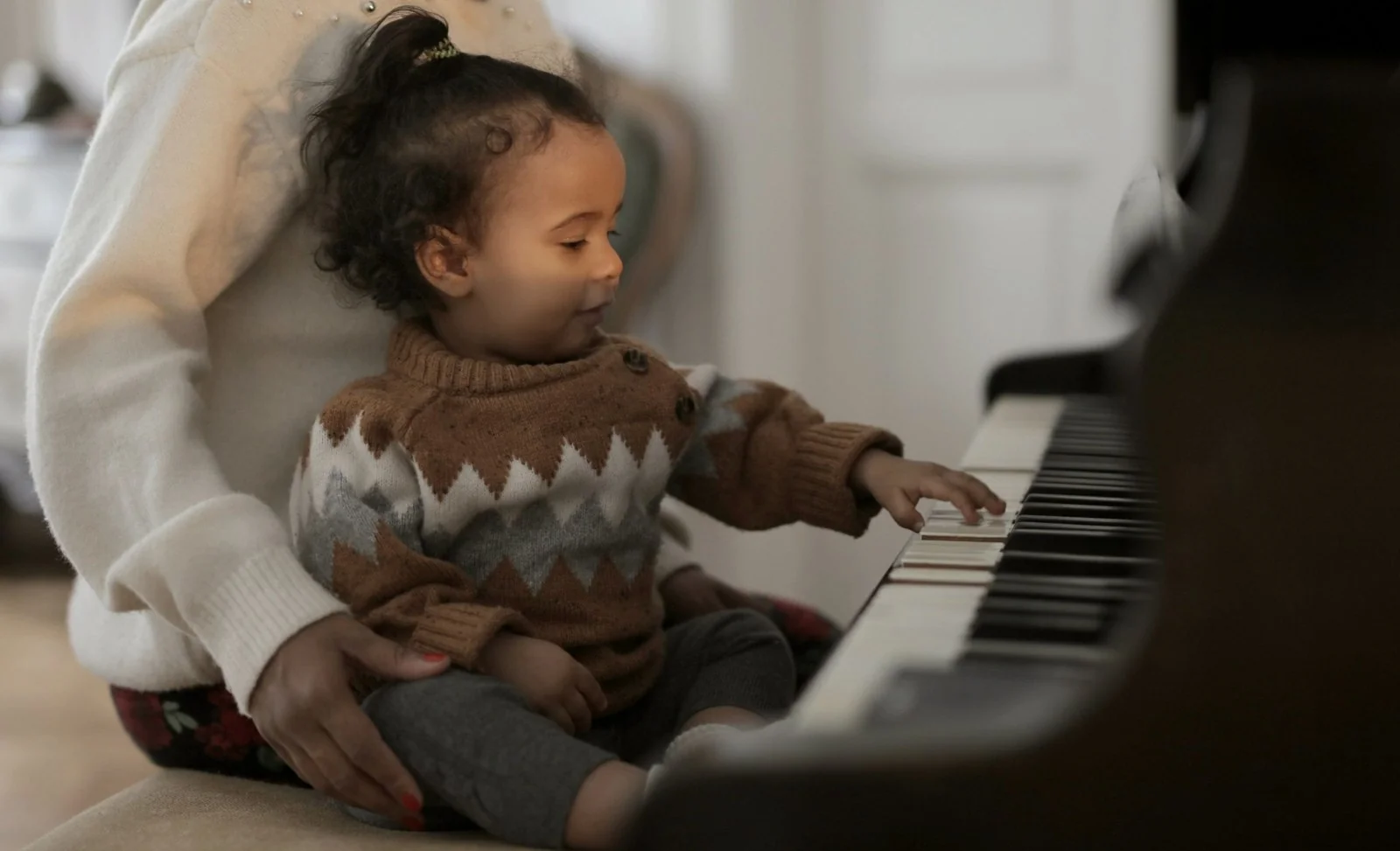 Child exploring piano keys with a parent