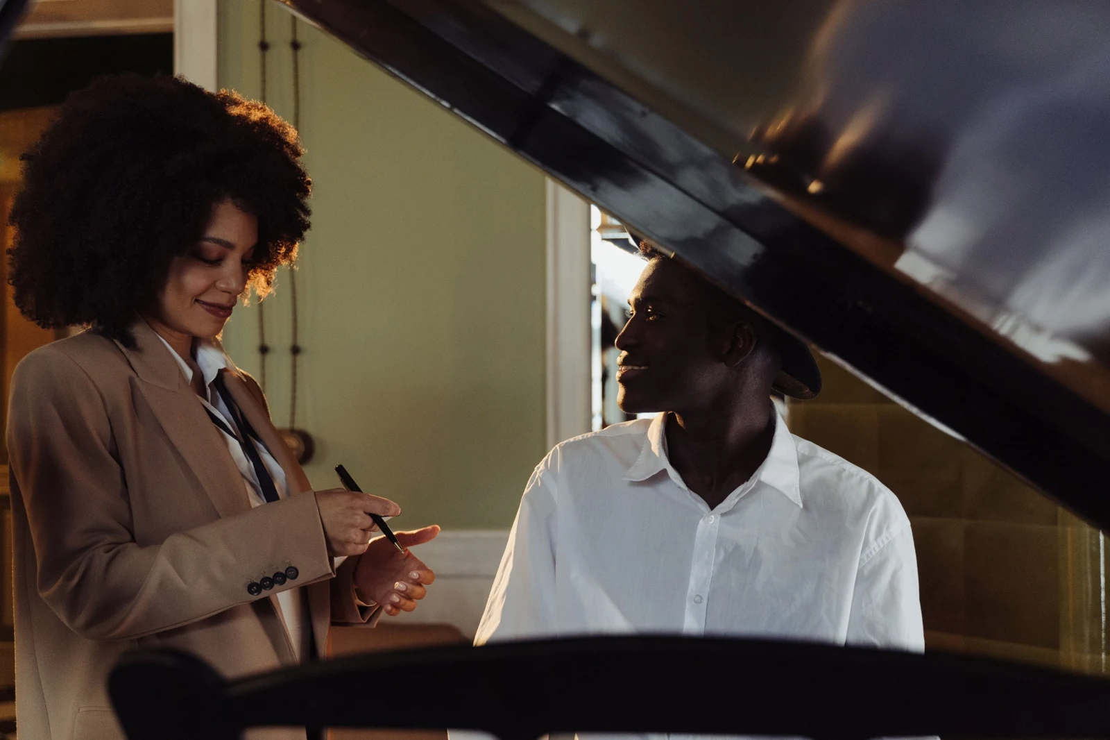 Two people sharing a moment beside a grand piano