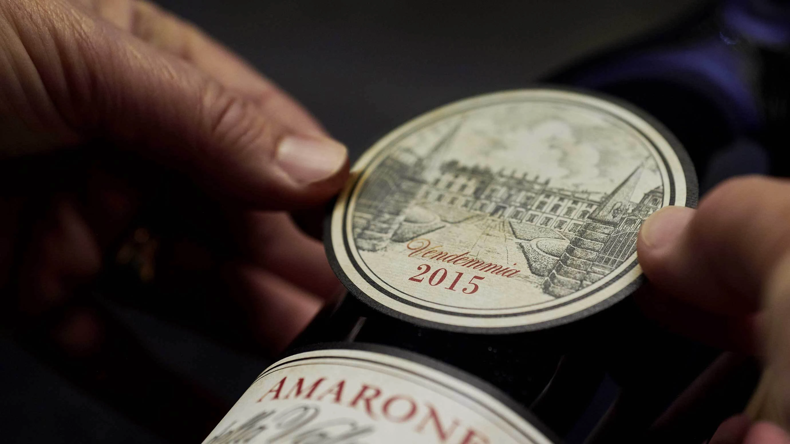 A 2015 vintage sticker being applied to a bottle of Bertani's Amarone