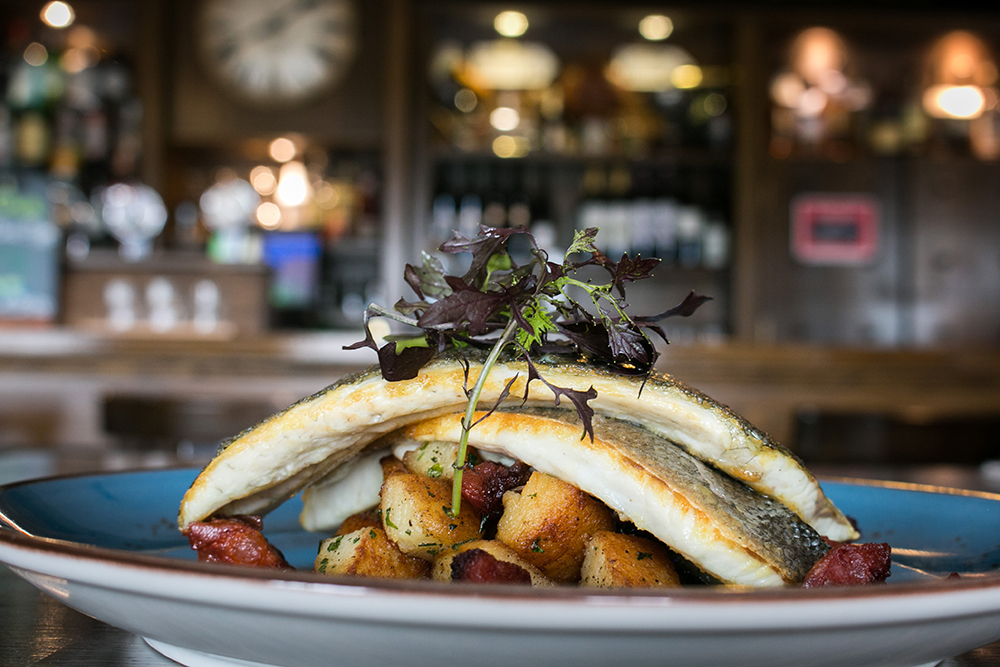 A plate of fried fish sitting on a bed of potatoes