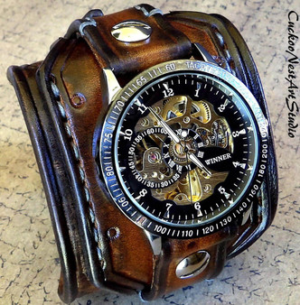 Angled view of steampunk leather cuff watch in aged brown full-grain leather with skeleton mechanical dial and wide leather watch band. Angled view of steampunk leather cuff watch in aged brown full-grain leather with skeleton mechanical dial and wide leather watch band.