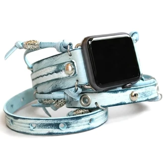 Distressed light blue leather Apple Watch wrap band with silver-tone studs, metal rings, and decorative beads.