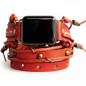 Close-up of red leather Apple Watch wrap band with layered straps, antique brass accents, and hand-tied leather details.