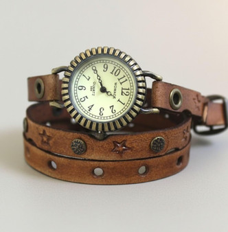 Women's leather watch front view showing antique brass face with cream dial and tan star stamped leather triple wrap band