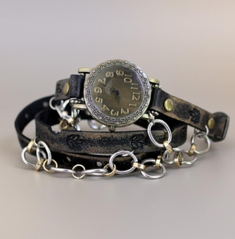 Women's leather watch in distressed black with large-link silver chain and antique brass face, triple wrap style coiled on gray background