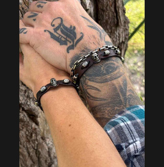 Couple wearing slim leather skull bracelets in brown