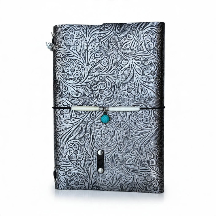 Moonlit Garden A5 refillable leather journal with metallic floral design, decorative elastic closure, and turquoise-colored charm.