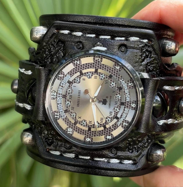 Close-up of handmade skull watch with black leather cuff and silver industrial dial