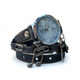 Angled view of women's dark leather wrap watch showing blue-gray dial, layered leather strap, silver-tone musical note and key charms.