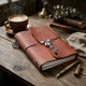 Burnt orange leather journal with skeleton charm on a rustic wooden desk beside coffee, vintage books, and a fountain pen.