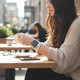 Woman wearing a distressed white leather Apple Watch wrap band while enjoying coffee at a café.