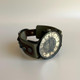 Handmade bohemian leather watch in olive green with gunmetal studs and distressed watch face, back angle view on white background