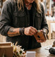 Person placing cash into a tan Western tooled leather bifold wallet, showing the wallet's size and appearance in hand.
 Copy both