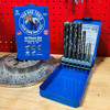 14-piece Bad Dog multipurpose drill bit set in open blue case displayed on workbench with retail packaging and brake rotor in background